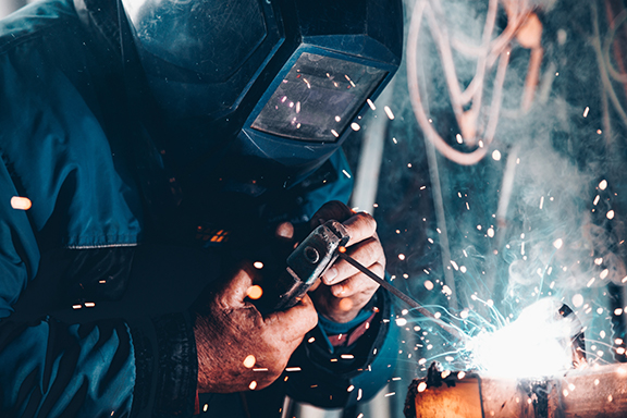 Person welding with blue sparks